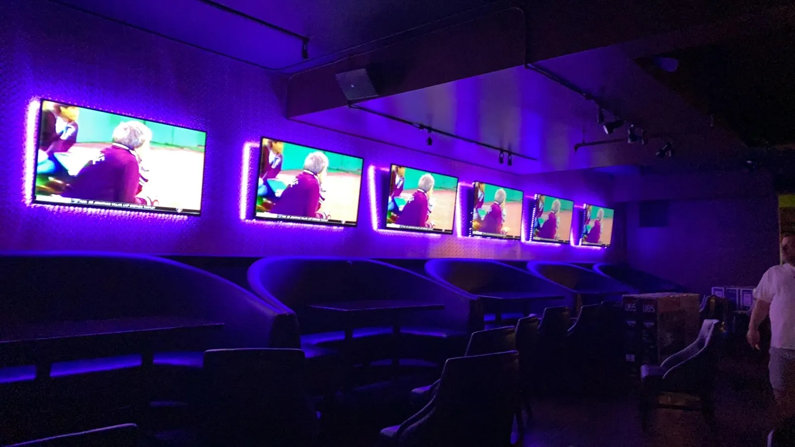 Lounge with a row of wall-mounted TVs and purple LED backlighting